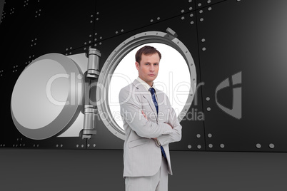 Composite image of serious businessman standing with his arms fo