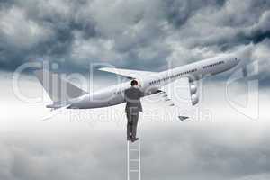 Composite image of businessman standing on ladder