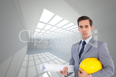 Composite image of serious architect holding plans and hard hat