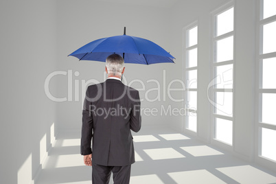 Composite image of businessman holding umbrella