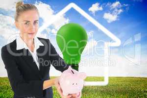 Composite image of businesswoman holding piggy bank