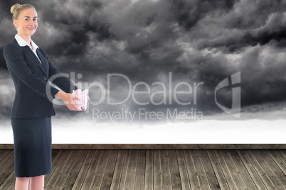 Composite image of businesswoman holding pink piggy bank