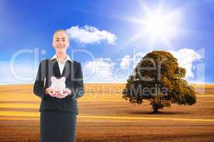 Composite image of businesswoman holding pink piggy bank