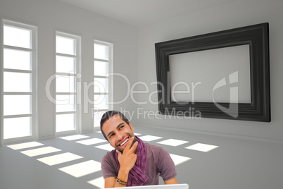 Composite image of thinking man sitting on floor using laptop an