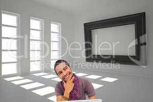 Composite image of thinking man sitting on floor using laptop an