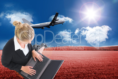 Composite image of businesswoman using laptop