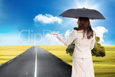 Composite image of elegant businesswoman holding black umbrella