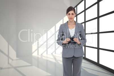 Composite image of young businesswoman with binoculars