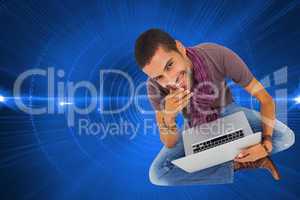 Composite image of thoughtful man sitting on floor using laptop