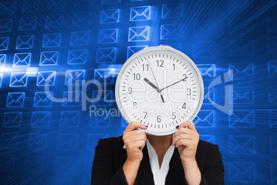 Composite image of businesswoman in suit holding a clock