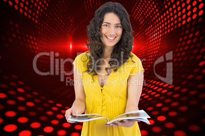 Composite image of cheerful curly haired brunette reading magazi