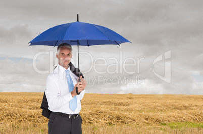 Composite image of businessman holding blue umbrella