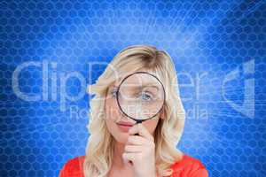 Composite image of fair-haired woman looking through a magnifyin