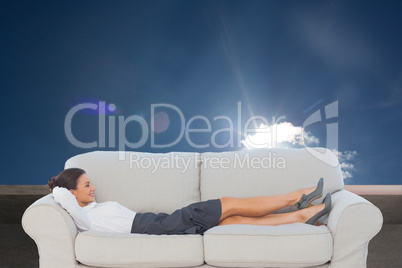 Composite image of smiling business woman lying down on the couc Composite image of smiling business woman lying down on the couc