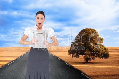 Composite image of shocked stylish businesswoman holding newspap