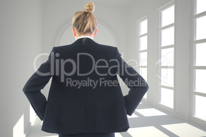 Composite image of businesswoman standing with hands on hips