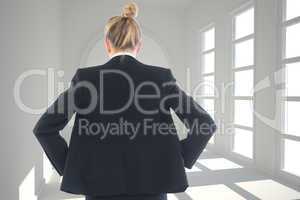 Composite image of businesswoman standing with hands on hips