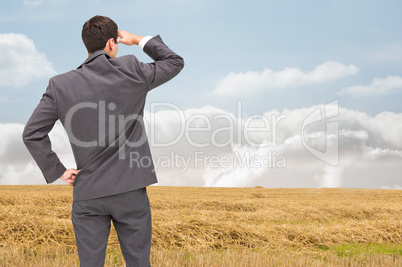 Composite image of businessman standing hand on hip