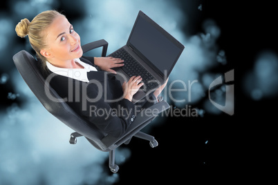 Composite image of businesswoman sitting on swivel chair with la