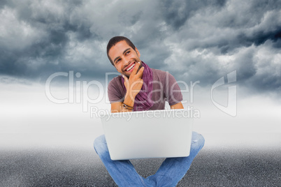 Composite image of thinking man sitting on floor using laptop an