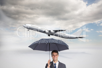 Composite image of happy businessman holding grey umbrella