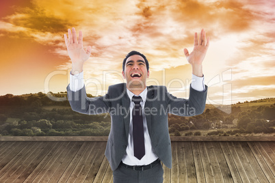 Composite image of excited businessman with arms raised