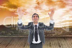 Composite image of excited businessman with arms raised