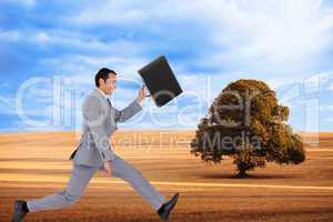 Composite image of businessman running with a suitcase