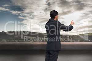 Composite image of thoughtful asian businessman pointing