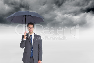 Composite image of happy businessman holding grey umbrella