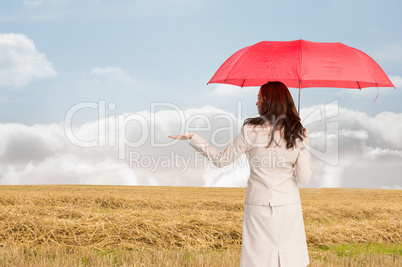 Composite image of businesswoman holding umbrella