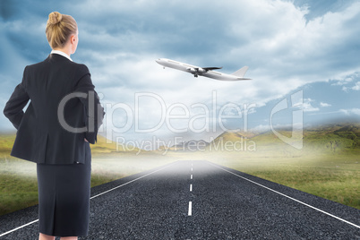 Composite image of businesswoman standing with hands on hips