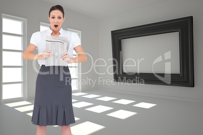 Composite image of shocked stylish businesswoman holding newspap