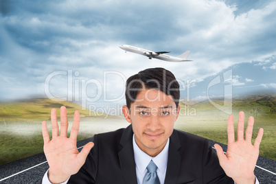 Composite image of smiling asian businessman holding hands up