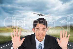 Composite image of smiling asian businessman holding hands up