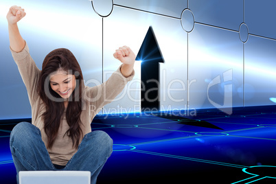 Composite image of brunette cheering while using laptop