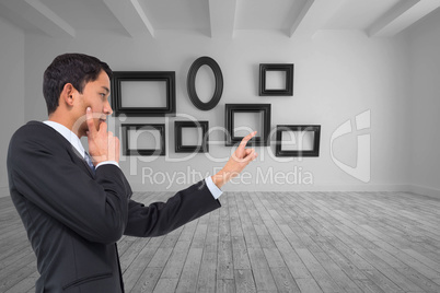 Composite image of thoughtful asian businessman pointing