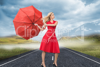 Composite image of beautiful woman posing with a broken umbrella