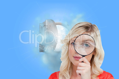 Composite image of fair-haired woman looking through a magnifyin