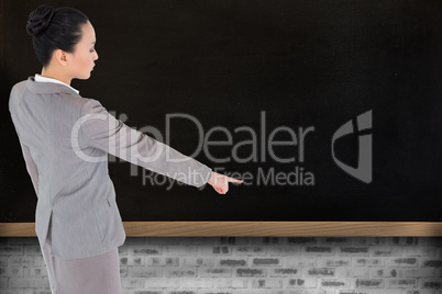 Composite image of unsmiling asian businesswoman pointing