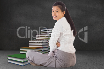 Composite image of businesswoman sitting cross legged smiling