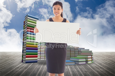 Composite image of businesswoman holding a placard