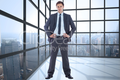 Composite image of serious businessman with hands on hips