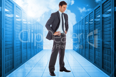 Composite image of smiling businessman with hands on hips