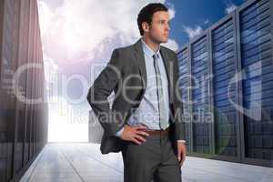 Composite image of businessman with hand on hip