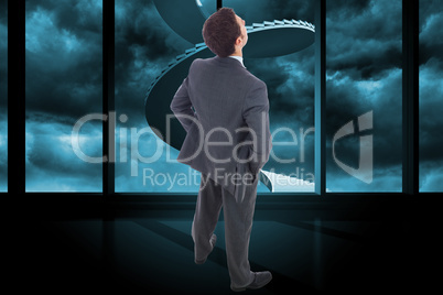 Composite image of businessman standing with hands on hips