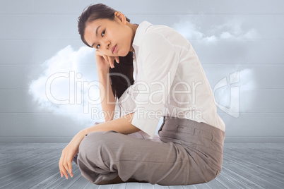 Composite image of businesswoman sitting cross legged leaning on