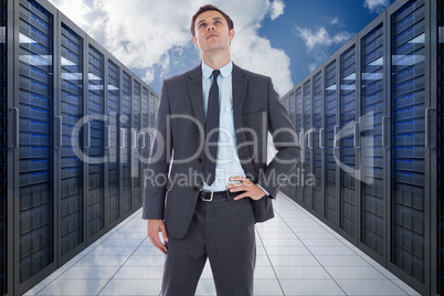 Composite image of serious businessman with hand on hip