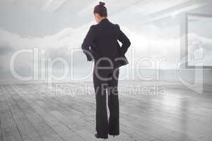 Composite image of businesswoman with hands on hips