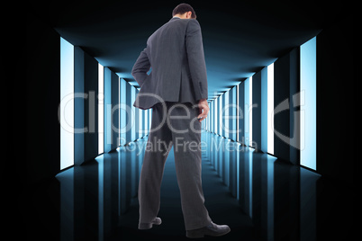 Composite image of businessman standing with hand on hip